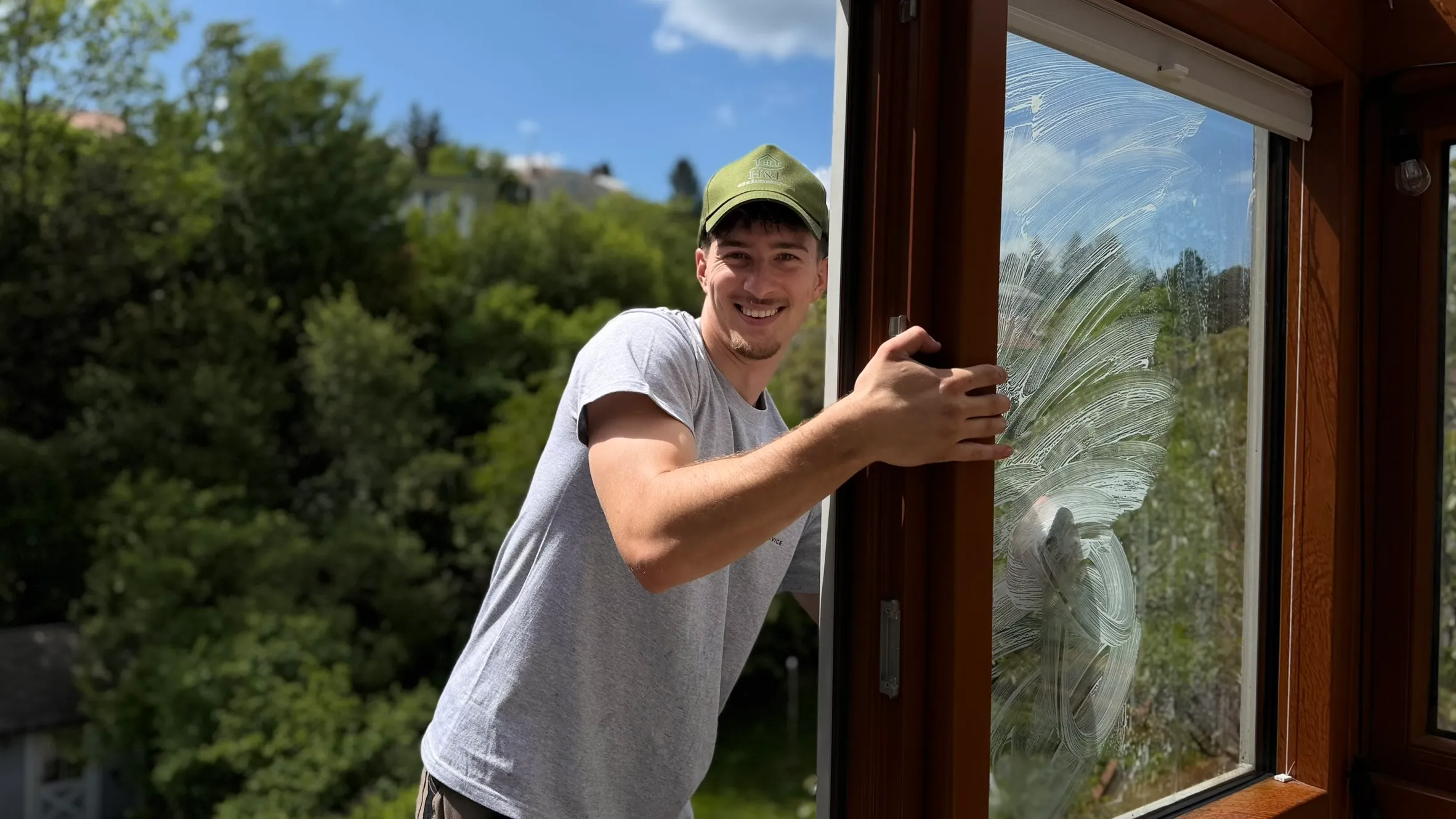 Mitarbeiter von H&F reinigt die Glasscheibe eines Holzfensters bei der Fensterreinigung in Wien