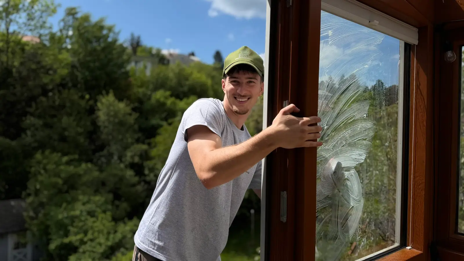 Mitarbeiter von H&F reinigt die Glasscheibe eines Holzfensters bei der Fensterreinigung in Wien
