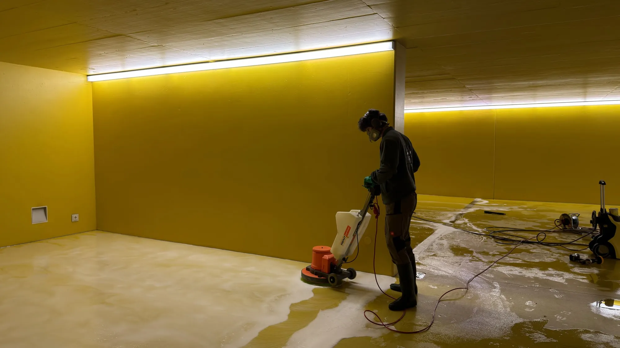 Mitarbeiter reinigt einen Hallenboden mit einer Bodenreinigungsmaschine