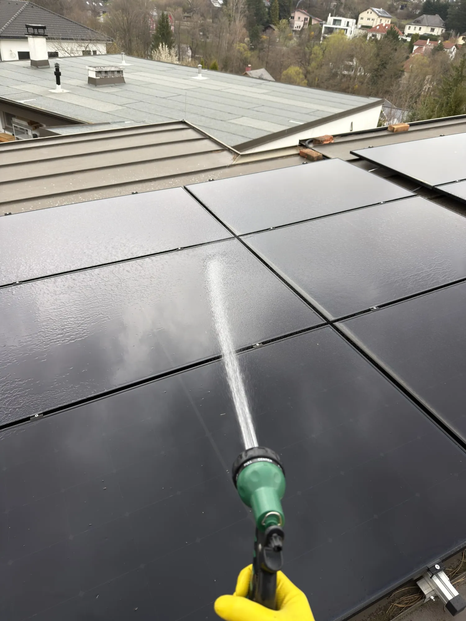 Mitarbeiter reinigt Photovoltaik-Module auf einem Dach mit einer Wasserstange