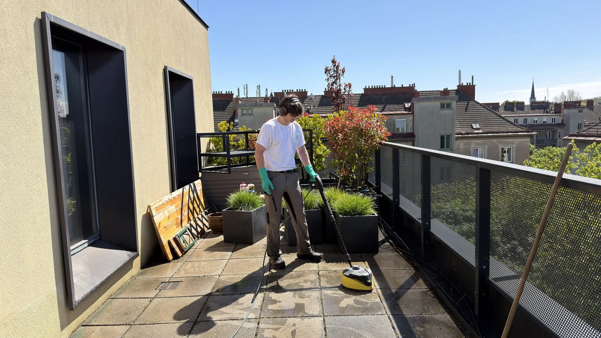 Reinigung eines Glasgeländers auf einer Dachterrasse mit Blick über die Wiener Dächer